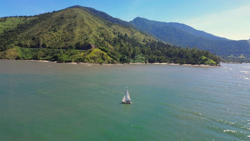 Veleiro navegando em frente às montanhas do Litoral Norte, fotografado do alto