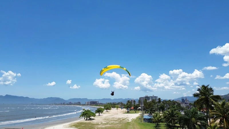 Voo de parapente sobre a praia e as montanhas