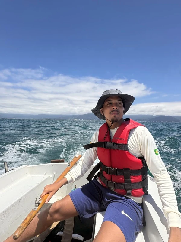 Eduardo Vieira a bordo de um veleiro, usando chapéu e colete salva-vidas